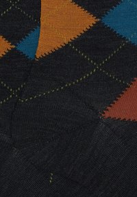 Calza con sfondo nero e motivo a rombi in blu, arancione e verde, che mostra un tessuto lavorato a maglia testurizzato.