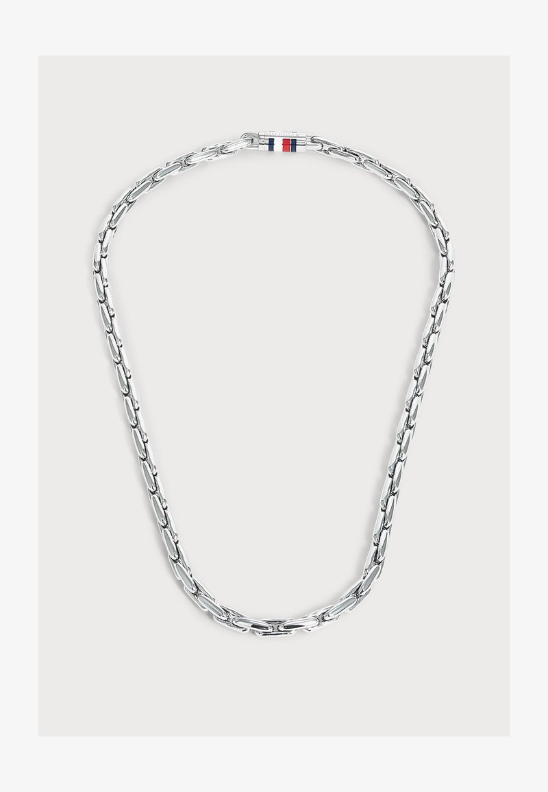 Collier chaîne en argent avec des maillons allongés et un fermoir présentant des rayures rouges, blanches et bleues sur un fond clair.