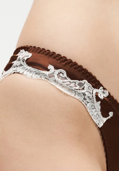 Κοντινή λήψη καφέ σατέν εσώρουχου με λευκή δαντέλα στη μέση και στο ισχίο.
