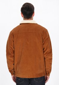 Brun kordfløjljakke med en cremefarvet faux shearling krave, med knapmanchetter og en lige skæring. Bagfra.