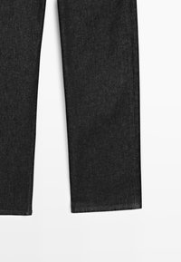Gambe di jeans in denim grigio scuro mostrate dritte e piatte, con orli laterali e inferiori visibili su sfondo bianco.