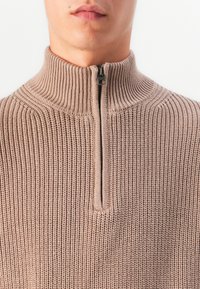 Beige Rippstrickpullover mit hohem Kragen und einem halben Reißverschluss. Verfügt über einen strukturierten Stoff und ein strukturiertes Design.