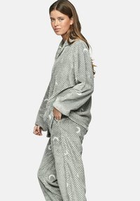 Ensemble de pyjama gris en tissu duveteux avec un motif texturé en forme de nid d'abeille. La chemise présente un col châle, et le pantalon a une coupe ample.