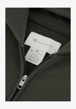 Donkergroene ritshoodie van zachte stof met een zilveren rits. Labels tonen "Champion" en maat "Small." Glad oppervlak, geen patronen.