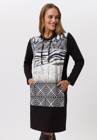 Robe noire à capuche avec un haut à motifs comprenant des rayures et des designs en maille, deux poches avant et des pois sur l'ourlet.
