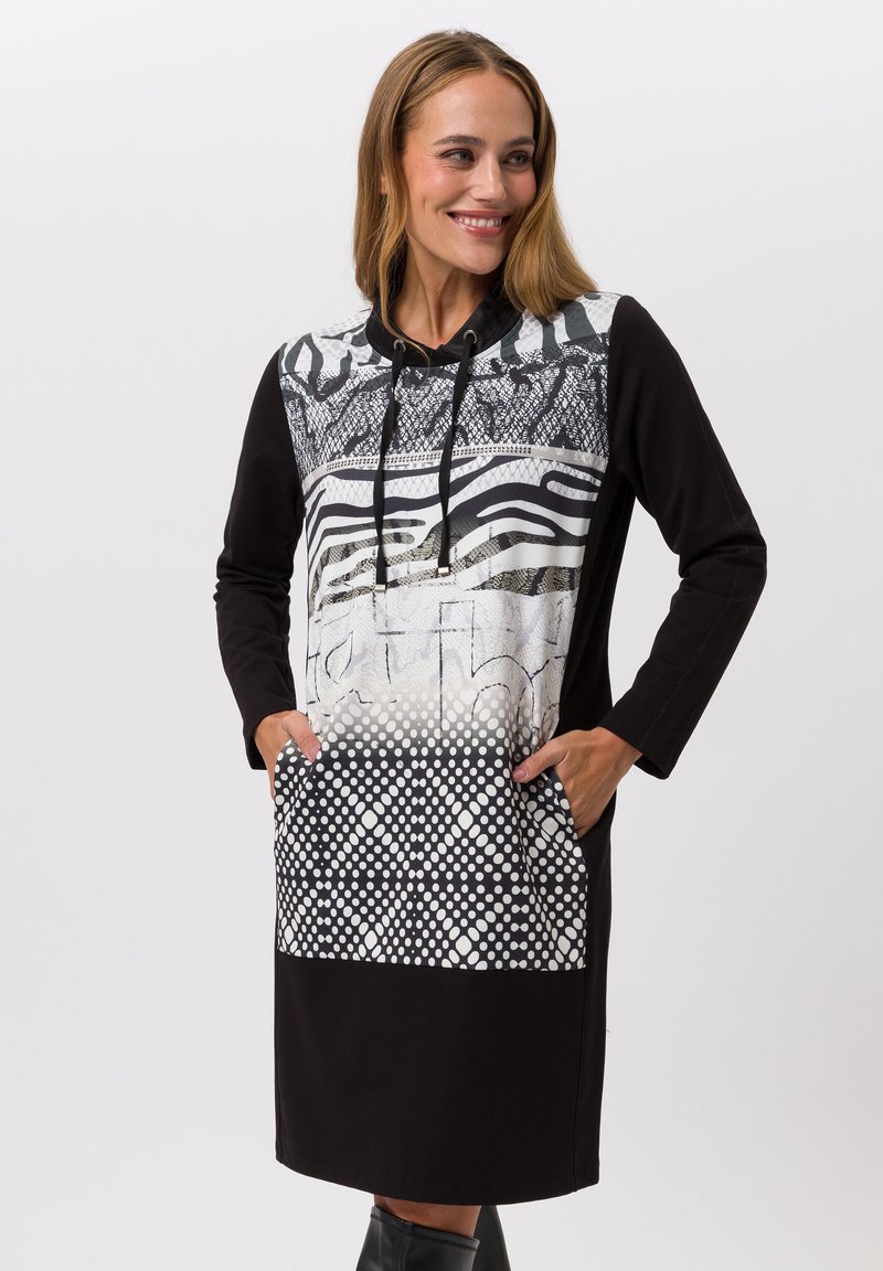 Robe noire à capuche avec un haut à motifs comprenant des rayures et des designs en maille, deux poches avant et des pois sur l'ourlet.