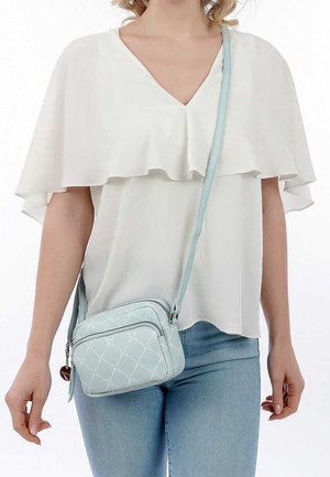 Helles blaues Crossbody-Design mit gestepptem Muster und silbernen Hardwareelementen. Verfügt über einen Reißverschluss und einen langen, verstellbaren Tragegurt.