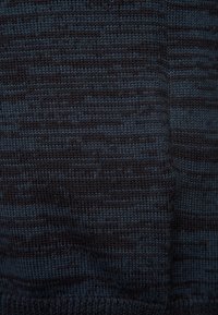 Tessuto lavorato a maglia di colore blu scuro che mostra un motivo testurizzato con diverse sfumature. La texture appare morbida e leggermente rigata in tutta la superficie.