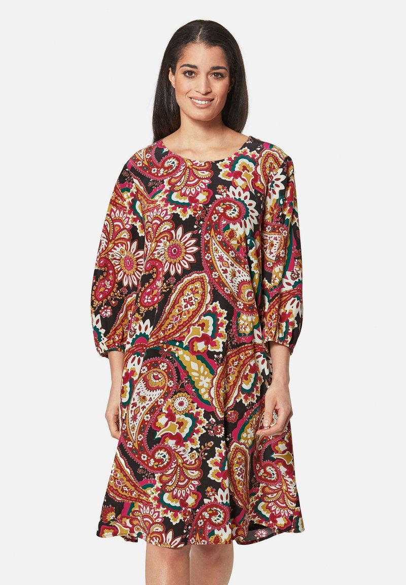 Bunt gemustertes Kleid im Paisley-Stil mit dreiviertel Ärmeln, einem runden Ausschnitt und einem ausgestellten Saum, das rote, grüne und gelbe Akzente aufweist.