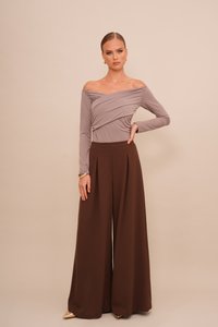 Top u boji taupe bez naramenica, prilagođenog kroja s naboranim detaljima; smeđe hlače širokog kroja visokog struka; glatka tkanina; zlatne cipele s oštrim vrhom.