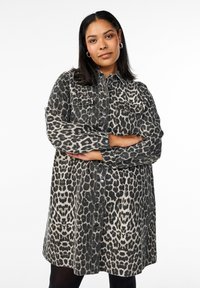 Vestido camisolín de mezclilla con estampado de leopardo, que cuenta con un cierre frontal de botones, dos bolsillos en el pecho, mangas largas y un corte relajado.