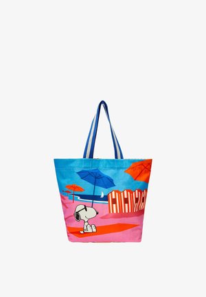 Tote bag met blauwe handvatten met Snoopy die een zonnebril draagt op een roze strand met oranje en blauwe parasols en gestreepte cabines.