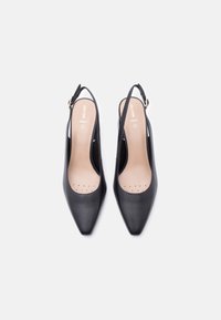 Μαύρα πέδιλα από δέρμα με λουράκι στο πίσω μέρος, μυτερή μύτη και σχέδιο με ανοίγματα, διαθέτουν μπεζ πάτο με τρύπες για αερισμό και χρυσή αγκράφα.