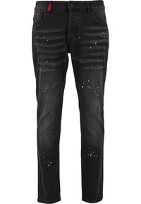 Jeans ajustados negros con áreas deslavadas, pequeñas manchas de pintura blanca y amarilla, detalles desgastados y un cierre de botón con bolsillos frontales.