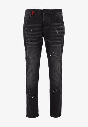 Jeans ajustados negros con áreas deslavadas, pequeñas manchas de pintura blanca y amarilla, detalles desgastados y un cierre de botón con bolsillos frontales.