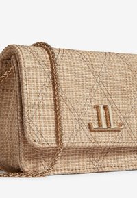 Tkaná crossbody taška z prútia v prirodzenej béžovej farbe so zlatým reťazovým popruhom, s prešívaným vzorom a výrazným zlatým logom na prednej strane.
