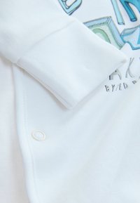 Witte katoenen shirt met lange mouwen, ronde halslijn en knoopsluiting, met kleurrijke bedrukking en een soepele textuur.