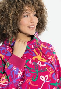 Felpa rosa con un motivo astratto colorato con accenti verdi, viola e gialli. Presenta un colletto alto e dettagli con cordino.