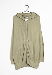 Olive green hooded cardigan with a zip front, large side pockets, and a textured knit fabric. Hangs on a black hook against a white background.