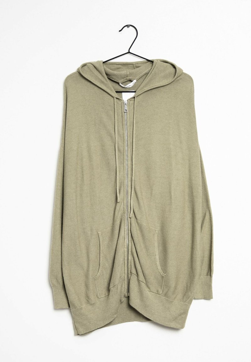 Olivgrüner Kapuzen-Cardigan mit Reißverschluss, großen seitlichen Taschen und einem strukturierten Strickstoff. Hängt an einem schwarzen Haken vor einem weißen Hintergrund.