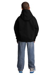 Czarna bluza z kapturem i kieszenią kangurką, w zestawie z luźnymi, jasnoniebieskimi dżinsami oraz szarymi sneakersami z niebieskimi akcentami.