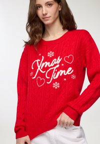 Czerwona sweter z dzianiny, z wzorem w warkocze, białym napisem "Xmas Time", serduszkami i płatkami śniegu. Ribbowane mankiety i dół.