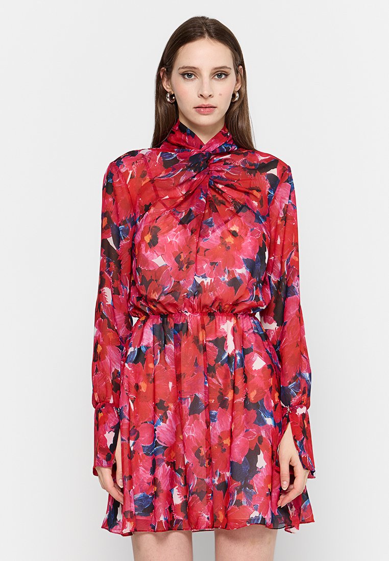 Bloemenjurk met een rood, roze en blauw patroon. Lange mouwen, geplooide halslijn, getailleerde taille en een uitlopende rok tot de knie.