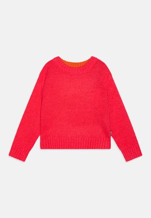 Rød strikket genser med ribbestrikkede ermer og hem, med en oransje indre krage. Kort, boxy design med lange ermer. Myk tekstur.