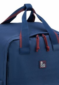 Zaino blu navy con manici a strisce rosse e blu, caratterizzato da una chiusura con zip e materiale in nylon testurizzato. Logo visibile sul davanti.