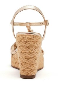 Sandalia de cuña con un tacón de yute natural trenzado, una correa metálica dorada en el tobillo y una banda suave en los dedos. Texturizada, con una base resistente para mayor soporte.