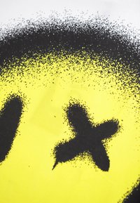 Yellow fabric featuring a black spray-painted smiley face with an X-shaped mark. The design has a gradient texture with scattered paint dots.