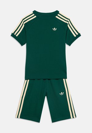 Mørkegrønt atletisk sæt med T-shirt med korte ærmer og shorts med cremefarvede striber på ærmer og sider, med lille logo på brystet og shorts.