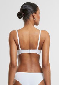 White bralette with slim adjustable straps, a hook closure, and a smooth texture, complemented by matching white bikini bottoms.