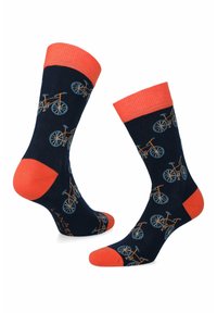 Granatowe skarpetki z pomarańczowymi akcentami mają wzór rowerowy w odcieniach niebieskiego i pomarańczowego. Gładka tekstura, długość do połowy łydki oraz wzmocnione palce i pięty.