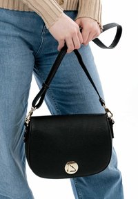 Borsa a tracolla in pelle nera con finitura testurizzata, hardware dorato e accento con logo circolare. Cinghia regolabile attaccata.