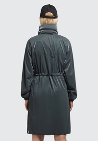 Vízhatlan szürke kabát magas gallérral, állítható derékpánttal és hosszú ujjakkal. Sima, fényes textúra, elasztikus mandzsettákkal.