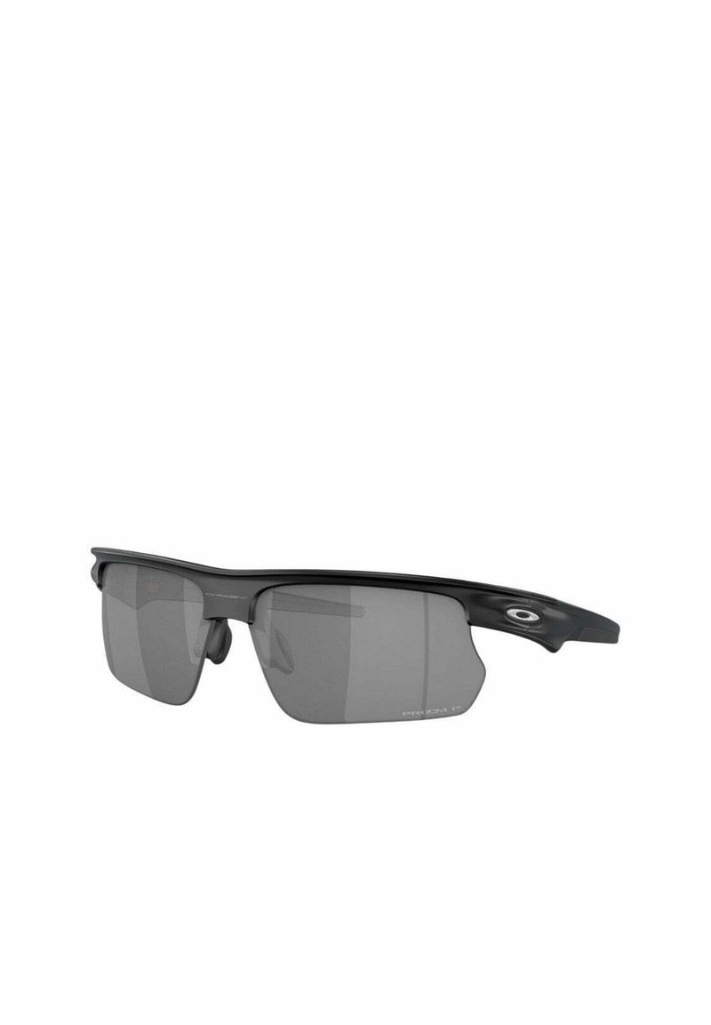 Gafas de sol deportivas con un marco negro mate, lentes grises, forma ergonómica y almohadillas nasales ajustables. Presentan un acento ovalado del logo en los laterales.