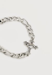 Ασημένιο βραχιόλι με αλυσίδα και λεπτομερή σταυρό με χάραξη "LOS ANGELES" σε λευκό φόντο.