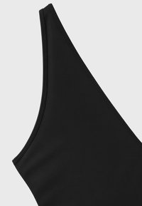 Gros plan de la partie supérieure d'un vêtement noir sans manches avec une texture simple et lisse et une bretelle étroite.