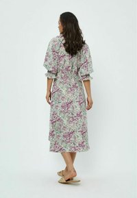 Robe midi florale en vert clair, avec des motifs violets et blancs, des manches bouffantes, une taille cintrée et une silhouette fluide.