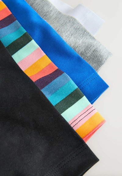 Pile de quatre t-shirts pliés montrant les ourlets en noir, rayures multicolores, bleu, gris et blanc sur une surface blanche.