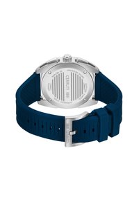 Reloj Cerruti 1881 con caja de acero inoxidable, correa de silicona azul y fondo plateado grabado con líneas verticales y detalles de marca.