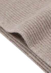 Beżowa prążkowana dzianina o miękkiej fakturze, z falistymi liniami i subtelnymi różnicami w odcieniach, złożona na siebie.