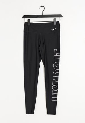 Zwarte Nike leggings die aan een zwarte hanger hangen met de witte slogan "JUST DO IT" verticaal gedrukt op het rechterbeen.
