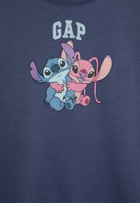 Felpa blu navy con una grafica di due personaggi dei cartoni animati, uno blu e uno rosa, con il testo "GAP" sopra di loro in azzurro chiaro.