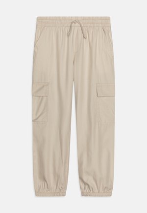Pantalon cargo beige avec taille élastique, cordon de serrage, poches latérales, poches à rabat sur les cuisses et poignets élastiques aux chevilles.