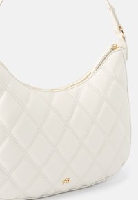Quilted white leather shoulder bag with gold zip closure and logo accent. Rounded shape and smooth texture enhance its design.