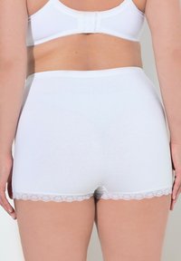 Witte katoenen ondergoed met een gladde textuur, middelhoog model en kantafwerking langs de beenopeningen, gezien vanachter.
