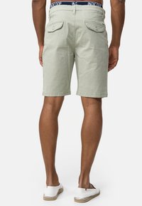 Hellgrüne Cord-Shorts mit geradem Schnitt, zwei Gesäßtaschen und einem marineblauen Bund mit Logodetails.