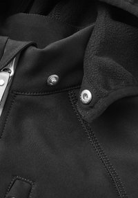 Black jacket with smooth fabric, featuring a fleece-lined collar. Notable metal snaps and stitching detail highlight the design.